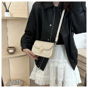 Gros plan sur le sac bandoulière carré blanc crème avec fermoir rotatif doré sur un mannequin