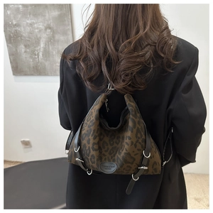 Detail einer Shopper-Tasche mit Leopardenmuster, schwarzen Lederbändern und Metallschnallen