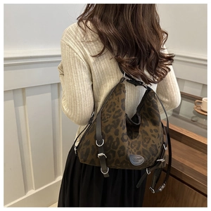 Detail der Totebag mit Leopardenmuster, schwarzen Lederriemen und Silberschnalle am Model