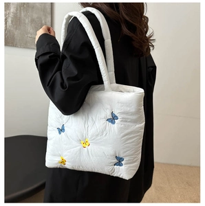 Close-up of butterfly embroidery on white quilted tote bag with soft cloud texture