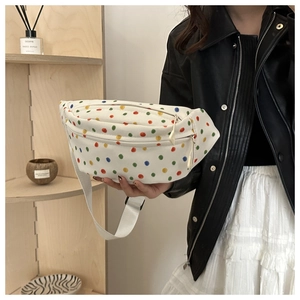 Detail of white canvas saddle bag with vibrant colorful polka dots and adjustable strap