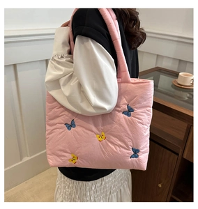 Pink quilted tote bag with colorful butterfly embroidery shown on a model's shoulder