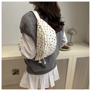 Detailed shot of a white canvas saddle bag featuring vibrant colorful polka dot patterns
