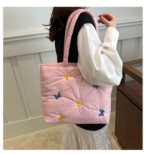 Close-up of pink quilted tote bag featuring colorful butterfly embroidery and soft padded strap