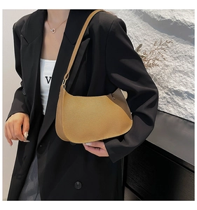 Detail of minimalist brown hobo bag with litchi texture and golden metal hardware