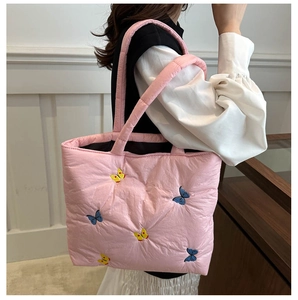 Detailed view of pink quilted handbag with delicate butterfly embroidery and padded texture