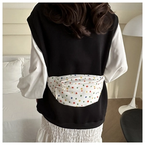Detail of white canvas waist bag with colorful polka dots worn as a crossbody bag