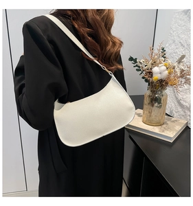 Close-up of white grainy hobo bag with gold hardware and long shoulder strap