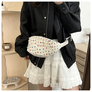 Detail of white saddle bag featuring colorful polka dots and an adjustable shoulder strap