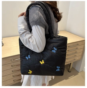 Quilted nylon tote bag with colorful butterfly embroidery shown on model's shoulder