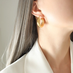 Élégantes boucles d'oreilles créoles dorées en U avec texture torsadée sur un mannequin