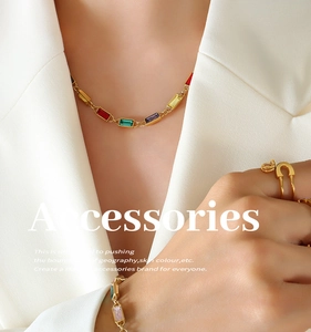 Detailed view of colorful rhinestone necklace and pin ring worn with a beige blazer