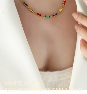 Detail of necklace with colorful rectangular rhinestones on a gold chain worn by a model
