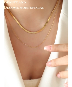 Close-up of double-layer gold snake chain and beaded necklace on a model