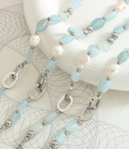 Détail de perles baroques et pierres naturelles bleues sur un collier à chaîne argentée