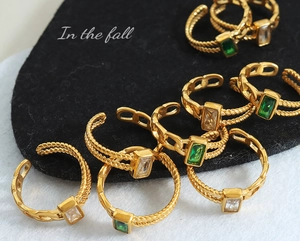 Détail d'une bague dorée torsadée avec pierres en zircon vert émeraude et blanc