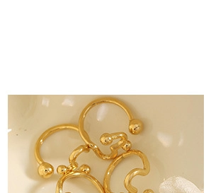 Close-up of gold geometric open hoops with sphere ends in a cream texture bowl