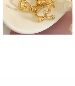Macro detail of gold geometric earrings featuring curved metal lines and spherical tips