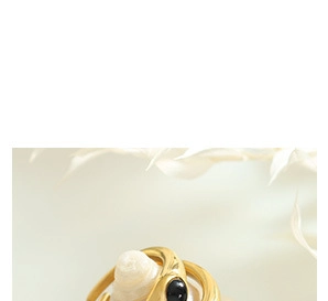 Détail d'une bague dorée irrégulière avec pierre noire sur un coquillage blanc spiralé