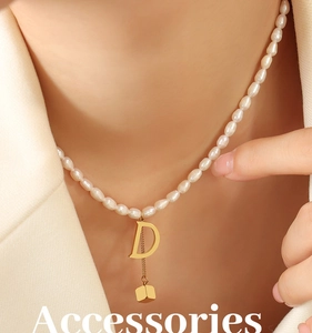 Macro detail of freshwater pearl necklace with gold letter D and cube tassel pendant
