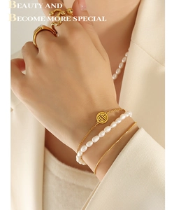 Detailed view of triple-layered gold bracelet set with natural freshwater pearls and charms