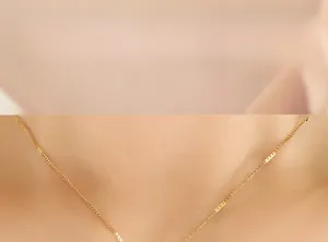 Détail d'un collier en chaîne dorée avec petites plaques en métal sur un mannequin