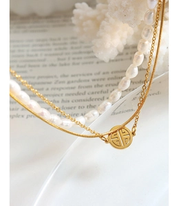 Close-up of double-layer necklace featuring white pearls and hollow circular gold pendant