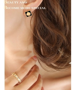 Détail de boucles d'oreilles coquillage doré et bague sertie de cristaux sur modèle