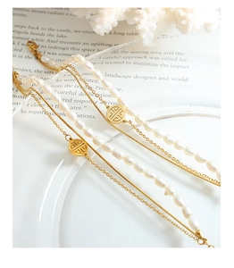 Detail of layered gold titanium bracelets with freshwater pearls and geometric pendants