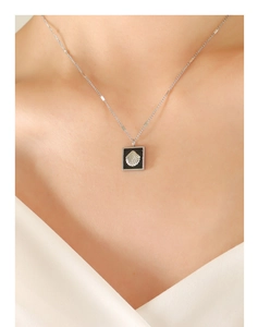Gros plan d'un collier en argent avec pendentif carré en relief de coquillage