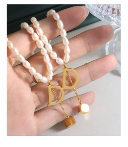 Detail of freshwater pearl necklace with gold letter D pendant and cube tassel