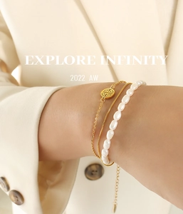 Detailed view of triple-layered gold bracelet set with natural pearls on a wrist