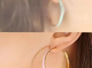 Close-up of model wearing pink enamel hoop earrings with textured gold metallic edges