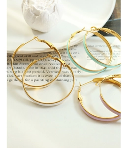 Close-up of three-color enamel hoop earrings with leverback closure on a white plate
