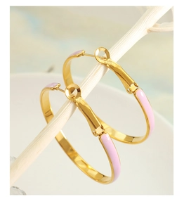 Detailed close-up of gold chunky hoop earrings with light pink enamel finish and pin closure
