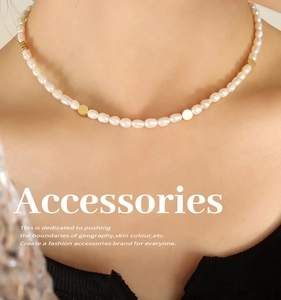 Detail view of a freshwater pearl necklace with gold bead accents on a female model
