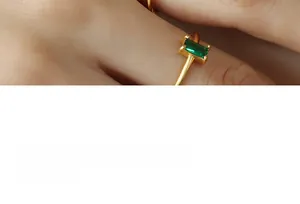 Close-up of minimalist gold ring featuring a rectangular green zircon in a 4-prong setting