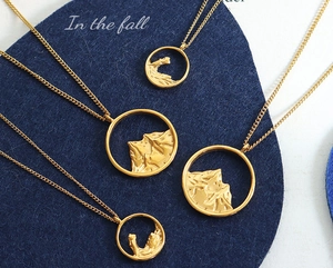 Close-up of golden mountain relief pendants with intricate layered textures and chains