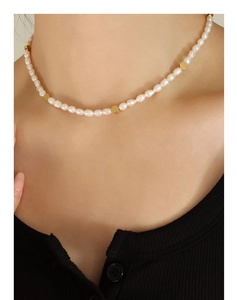 Detail view of irregular freshwater pearl necklace with golden metal beads on model