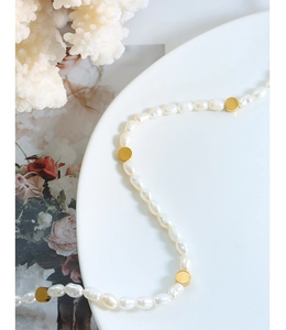 Macro view of freshwater pearl necklace with irregular golden bead accents on ceramic