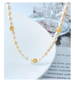 Detail of freshwater pearl necklace with golden beads on white ceramic plate