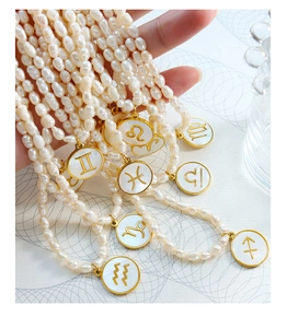 Detail of freshwater pearl necklace with gold-framed zodiac sign shell pendants