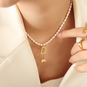 French style pearl necklace with gold letter D and cube pendant on female model