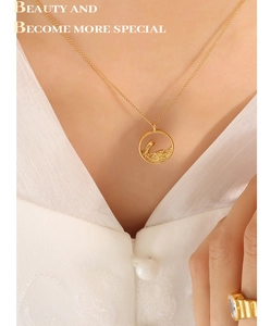 Detail view of a gold-plated necklace with circular wave pendant on a fashion model
