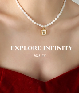 Detailed view of a gold necklace featuring a white shell butterfly pendant and pearls