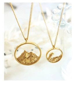 Detailed close-up of gold mountain relief pendants with elegant matte finish on cross chains