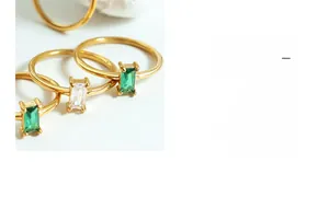 Detailed view of three minimalist gold rings featuring square-cut green and white zircons