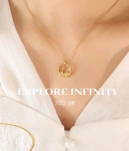 Close-up of golden hollow pendant with wave carving on model in white silk top