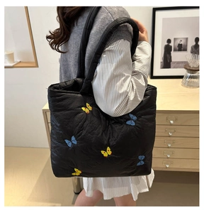Close-up of black quilted tote bag featuring vibrant yellow and blue butterfly embroidery