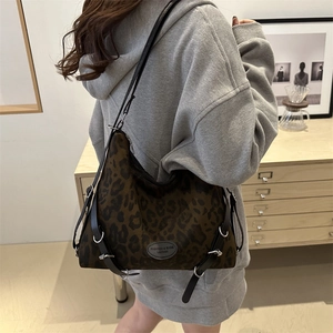 Braune Totebag mit Leopardenmuster und schwarzen Lederriemen am Modell im Innenraum